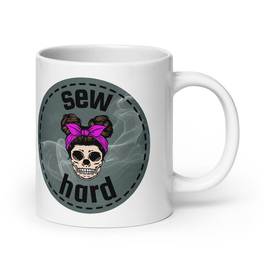 White ceramic mug with Sew Hard skull design featuring pigtail buns, pink bow, and smoky sage green background – sewing gift for quilters and sewists